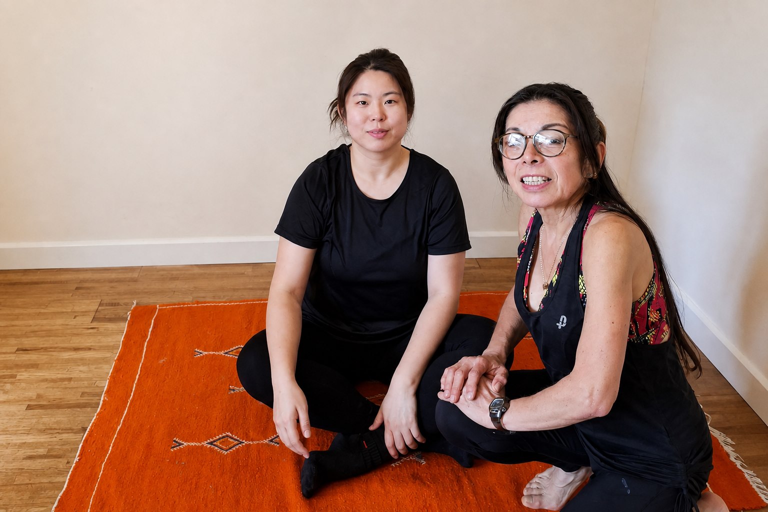Instructor and participant seated on an orange mat at the start of a guided movement session