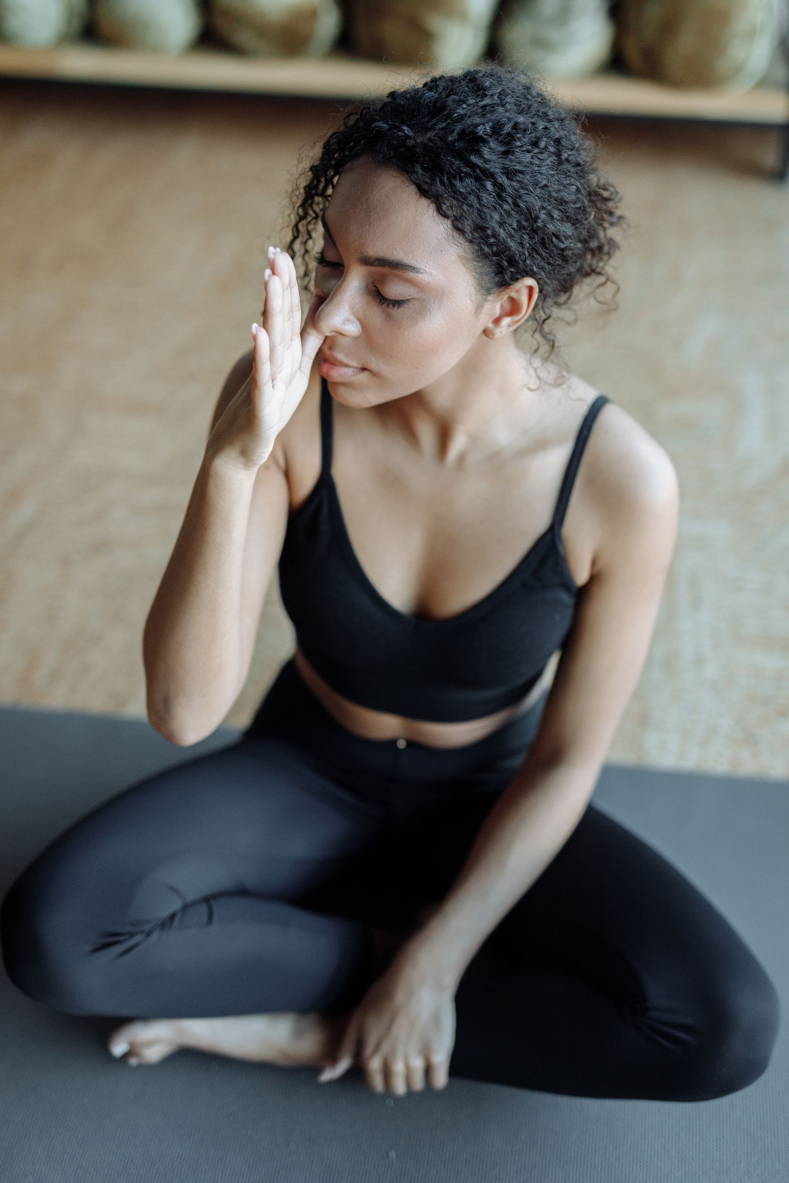 Woman sitting quietly on a mat with her eyes closed, taking a pause
